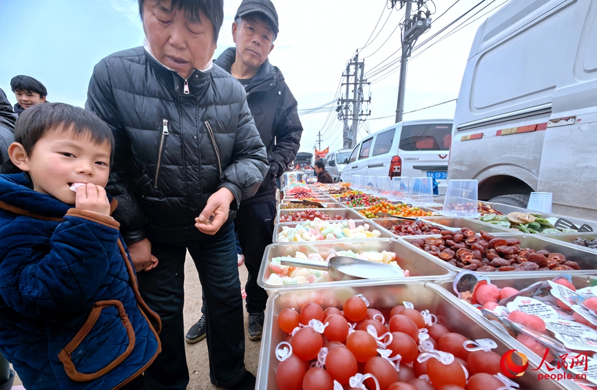 老人牵着孩子挑选糖果。人民网记者 宋芳鑫摄